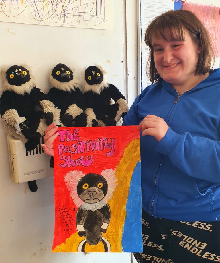 Photo of Julia with her three lemurs, holding a poster for her show