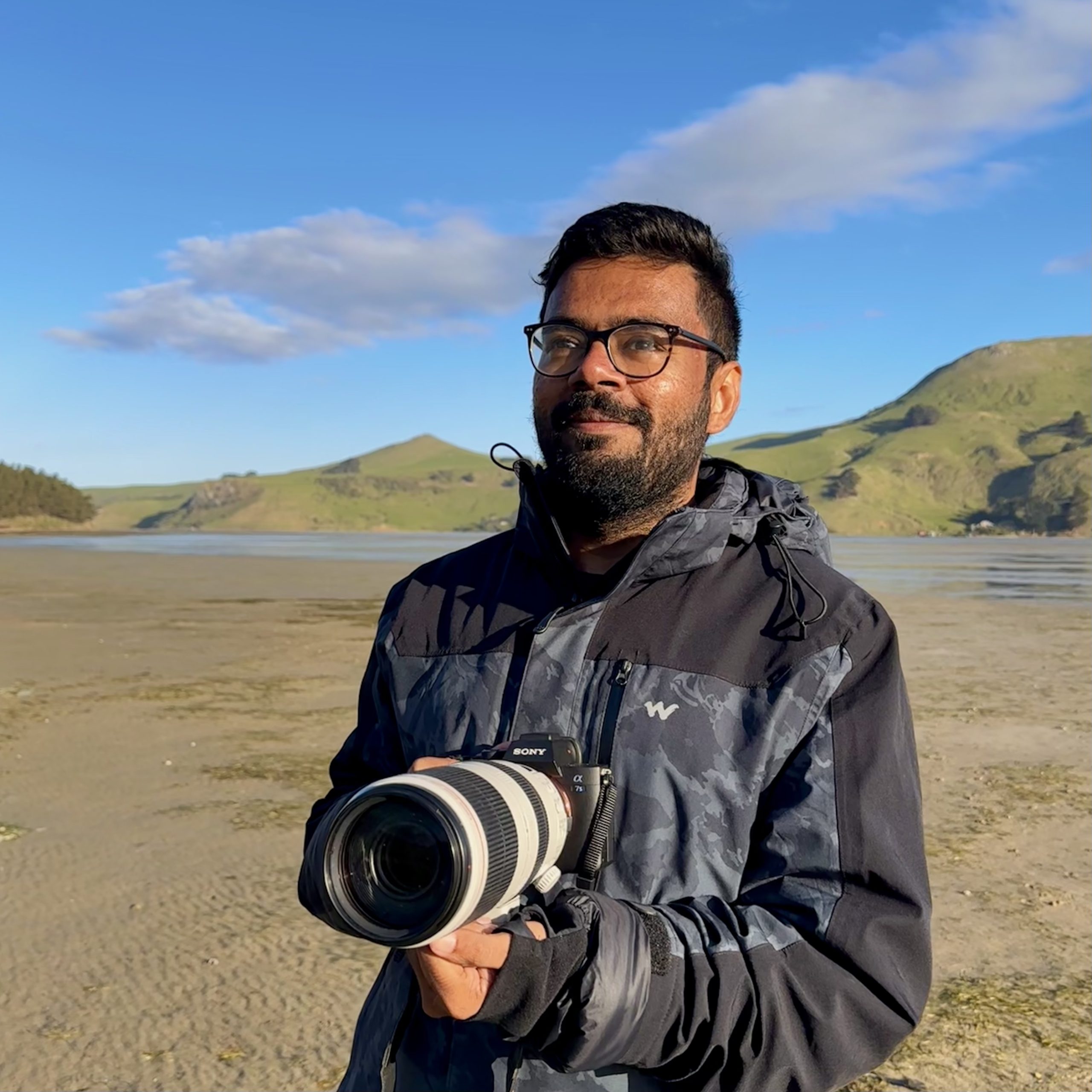 Photo of Karthic on a beach with his camera