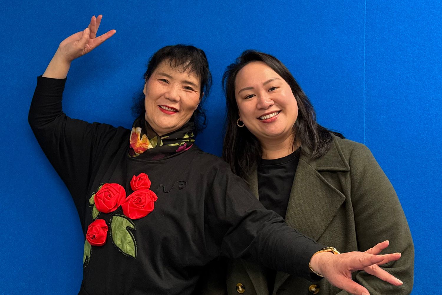 Weidi and Racee in front of blue wall. Hosts of The Chinese Culture Show