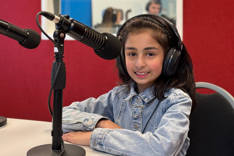 Khirad Ahmed from Global Kids with Khirad sits infront of a microphone.