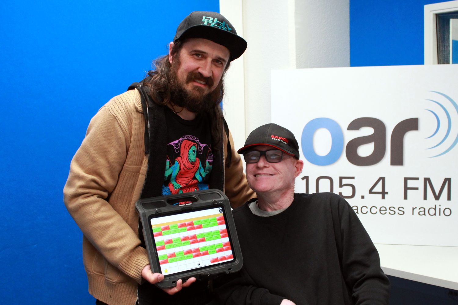 Photo of Steve Marshall and Phil Rogers in OAR FM studio holding Phil's Tablet that assists him with voicing the show
