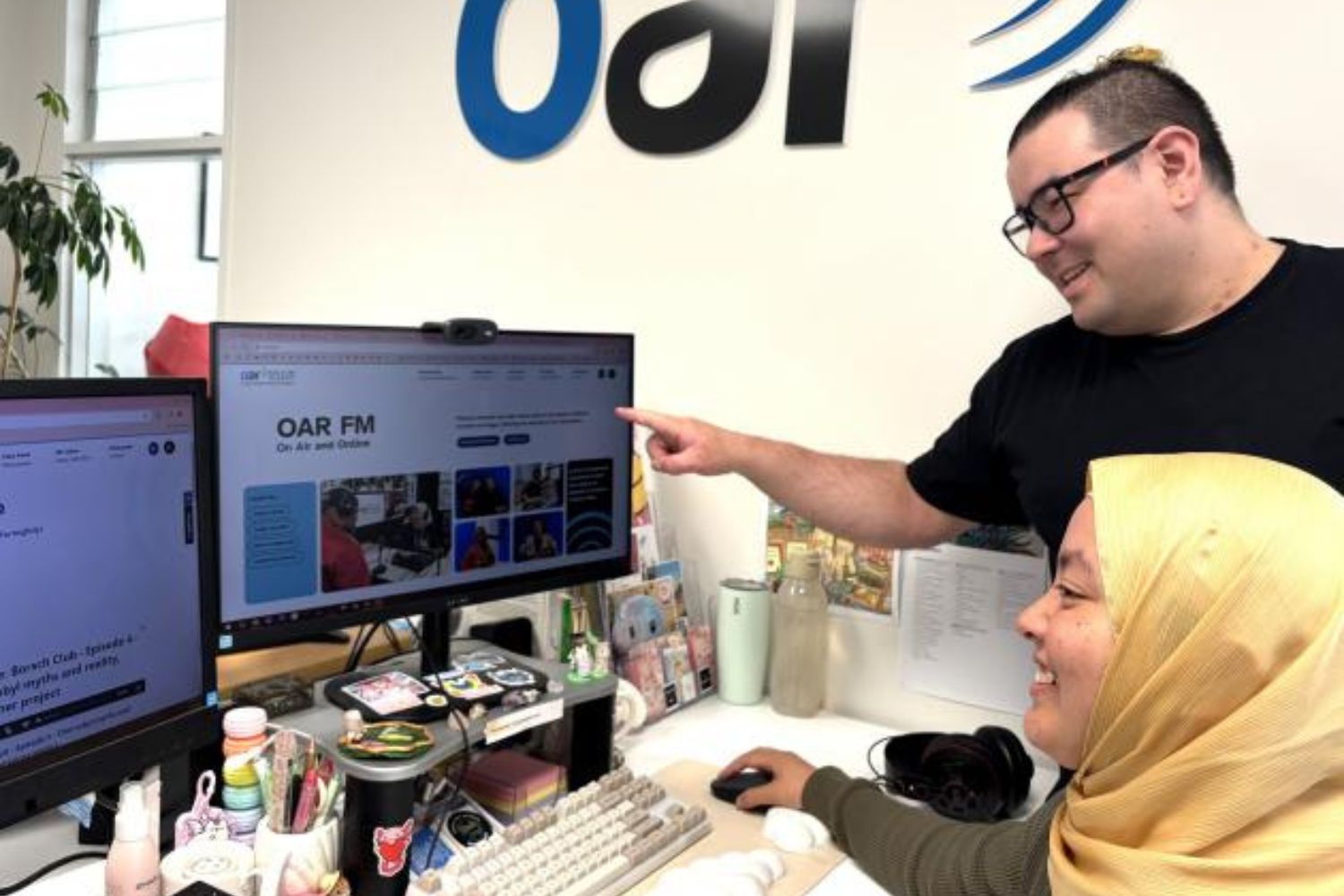 OAR operations director Dominic Angelo-Laloli (standing) and community connector Arina Aizal check out the station’s new website