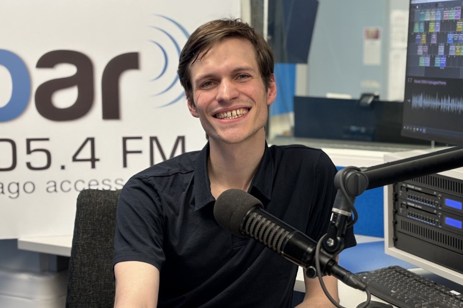 Host Nathan Woodfield in the recording studio in front of OAR FM sign