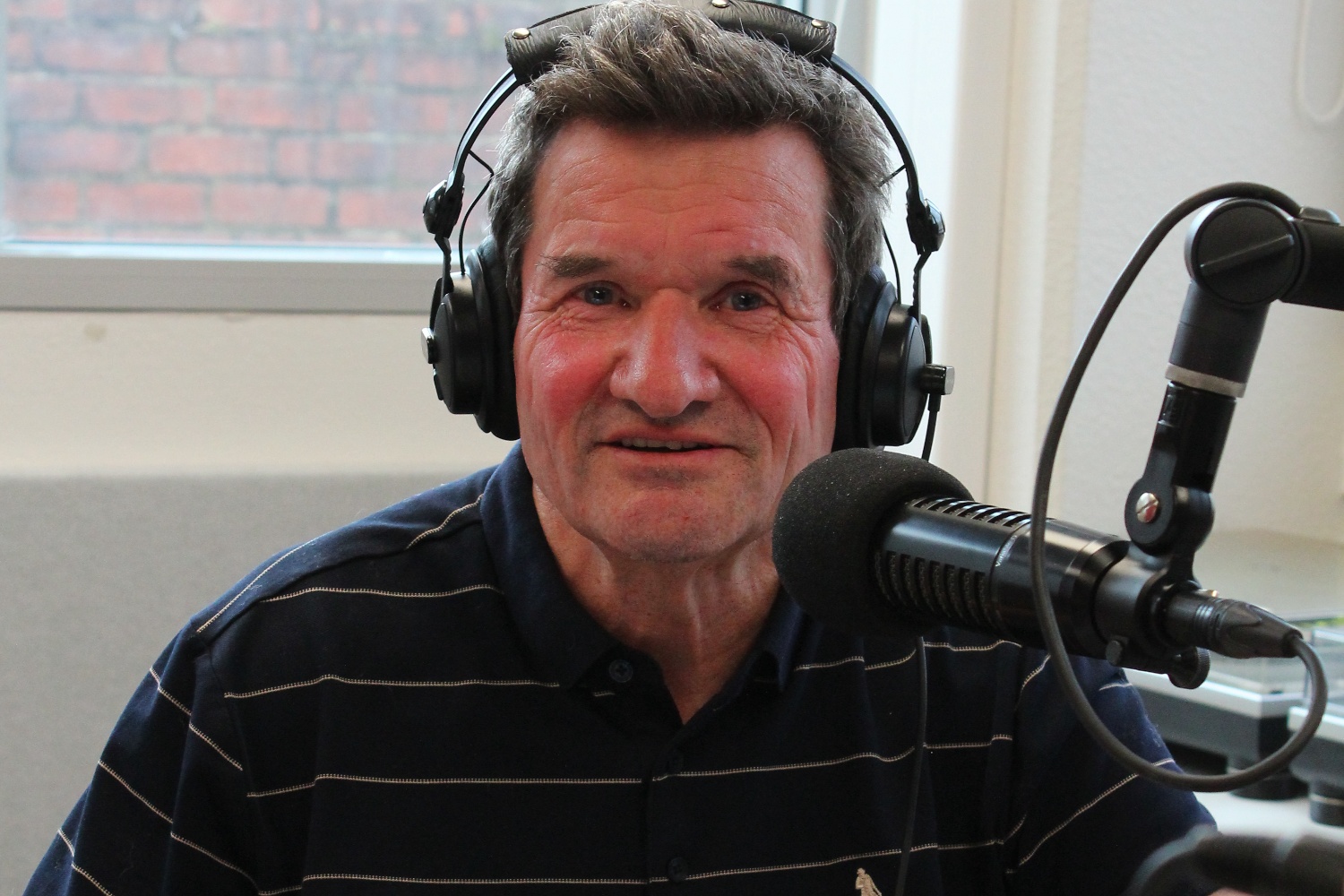 Photo of Alistair Addis in OAR FM Studio, wearing headphones and talking into the mic